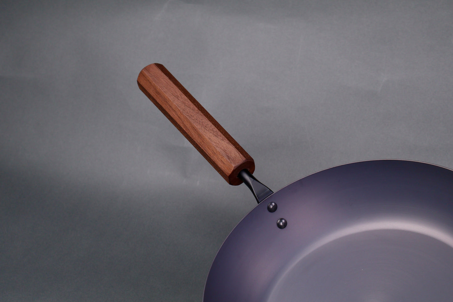 wide low bluish grey black carbon steel saute pan octagonal wood handle in grey background