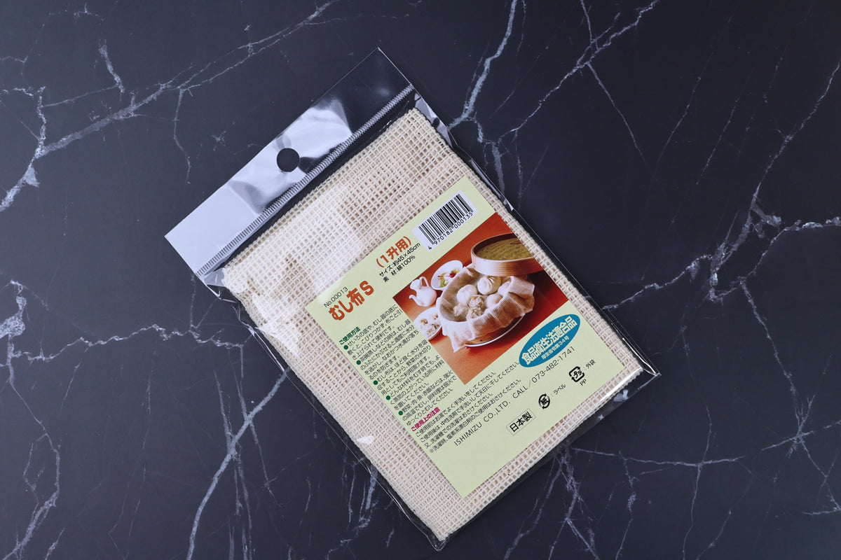 Ishimizu mushibu steamer cloth packaging angled on marble, showing label and cotton cloth texture through clear plastic