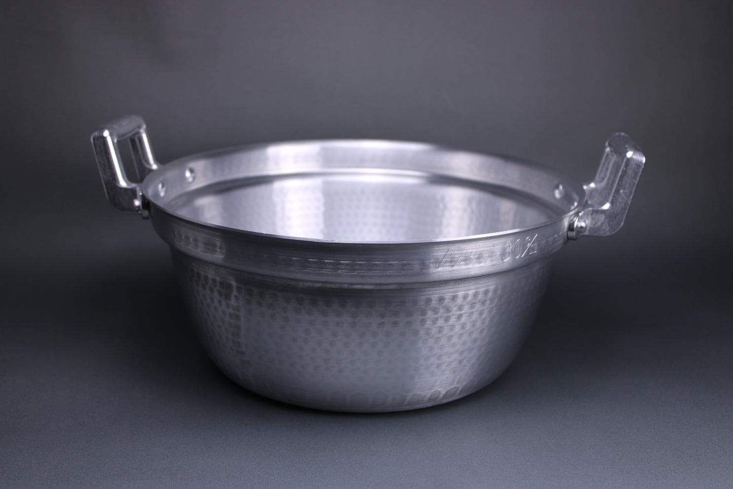 close up shot of aluminum steaming and stew pot with two large handles and internal ledge which holds steaming baskets and drop lids the textured surface is dimpled from the hammering technique