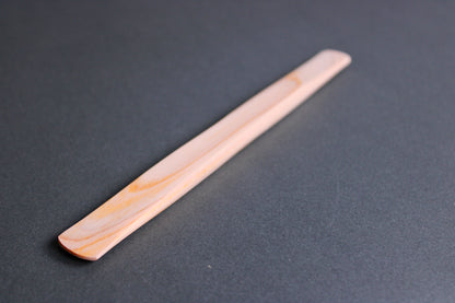 long thin flat natural wood tone hinoki spreader in dark grey backdrop 