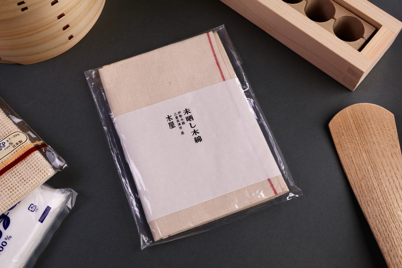 set of three cotton kitchen cloths by kiya with whitish tan color slightly coarse texture wrapped by white sheet in clear plastic package