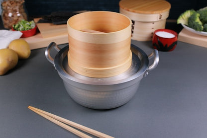 Close up shot of dantsuki pot with twenty one cm steam ring on top and hinoki wood round container for tofu making on top with wood lid inside kitchen background showing vegetables wood japanese kitchenware