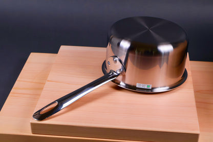 japanese steel saucepan made in Niigata underside showing shiny surface atop wood boards with dark grey background