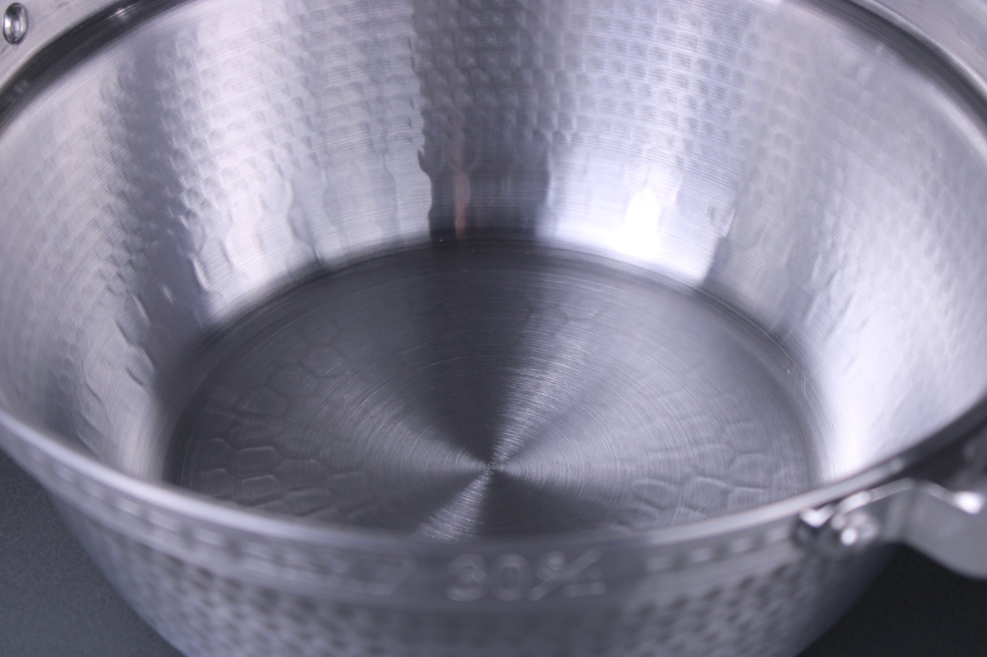 close up image of steaming pot with hammered surface and silver color with grey background