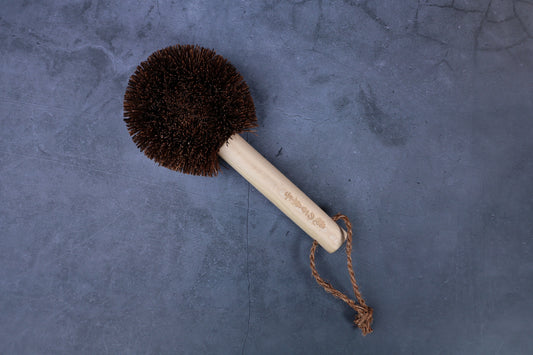 Kamenoko Ironware Pro Scrubber on concrete, showing engraved Japanese handle text and jute hanging loop clearly