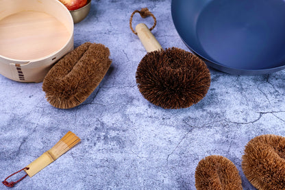 Kamenoko Ironware Pro Scrubber on concrete with bento box, carbon steel pan, and other kitchen tools, styled scene
