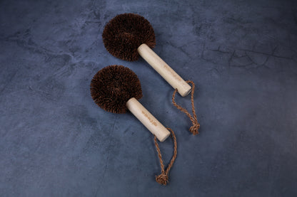 Two Kamenoko Ironware Pro Scrubbers side by side on concrete, showing size difference and rope hangers