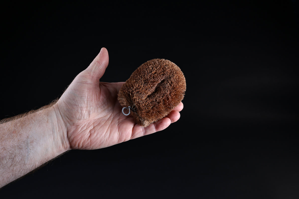Kamenoko Tawashi No. 1 scrub brush — held in palm showing natural palm fiber bristle texture