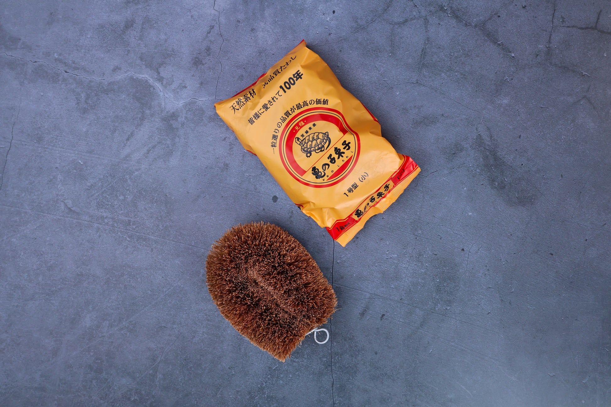Kamenoko Tawashi No. 1 small scrub brush — brush and original Japanese packaging flat lay
