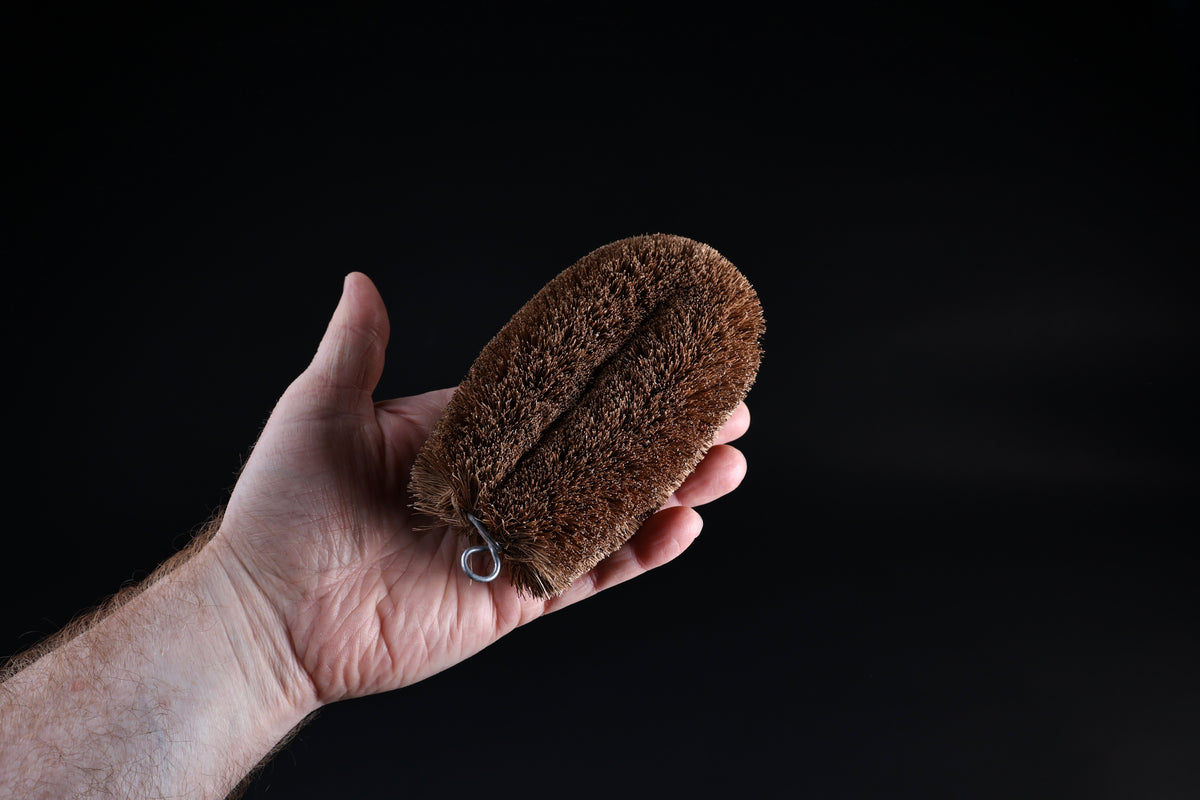 Kamenoko Tawashi No. 3 medium scrub brush — held in hand showing full oval form and bristle depth