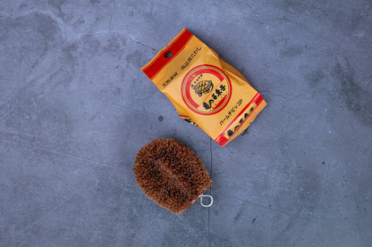 Kamenoko Tawashi palm-size scrub brush — brush and original Japanese packaging flat lay

