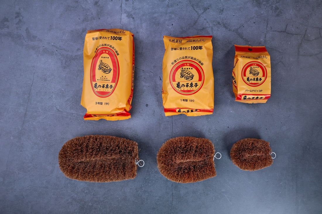 Kamenoko Tawashi scrub brush — all three sizes with packaging arranged overhead for size comparison