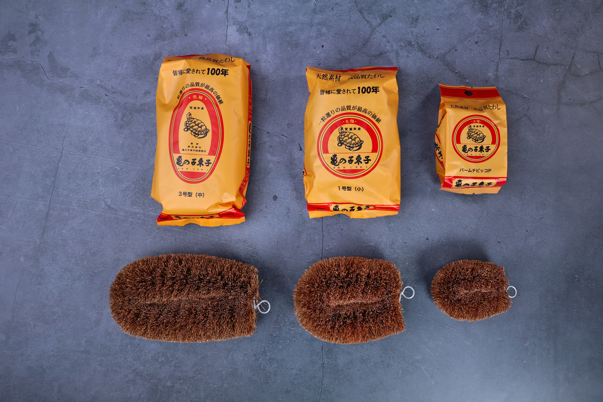 Kamenoko Tawashi scrub brush — all three sizes with packaging arranged overhead for size comparison