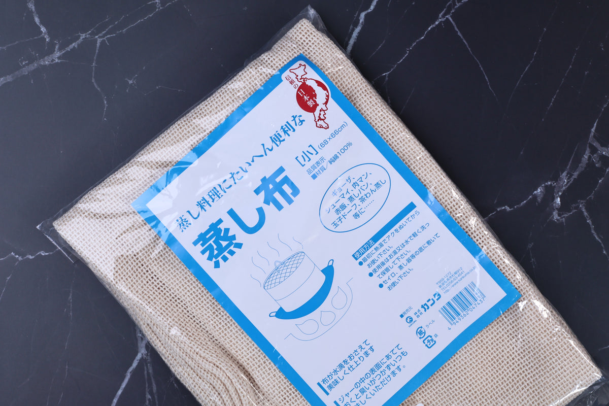 Kanda steamer cloth 蒸し布 packaging close angled view, blue label and open-weave cotton cloth texture clearly visible