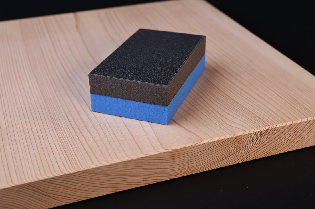 Kato Sangyo cutting board scraper — placed on hinoki cutting board showing scraper size and abrasive surface