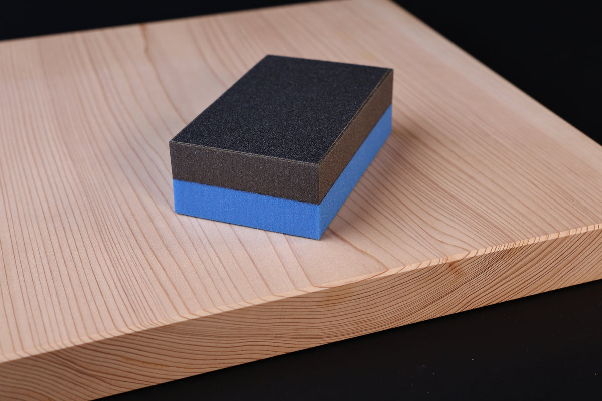 Kato Sangyo cutting board scraper — placed on hinoki cutting board showing scraper size and abrasive surface