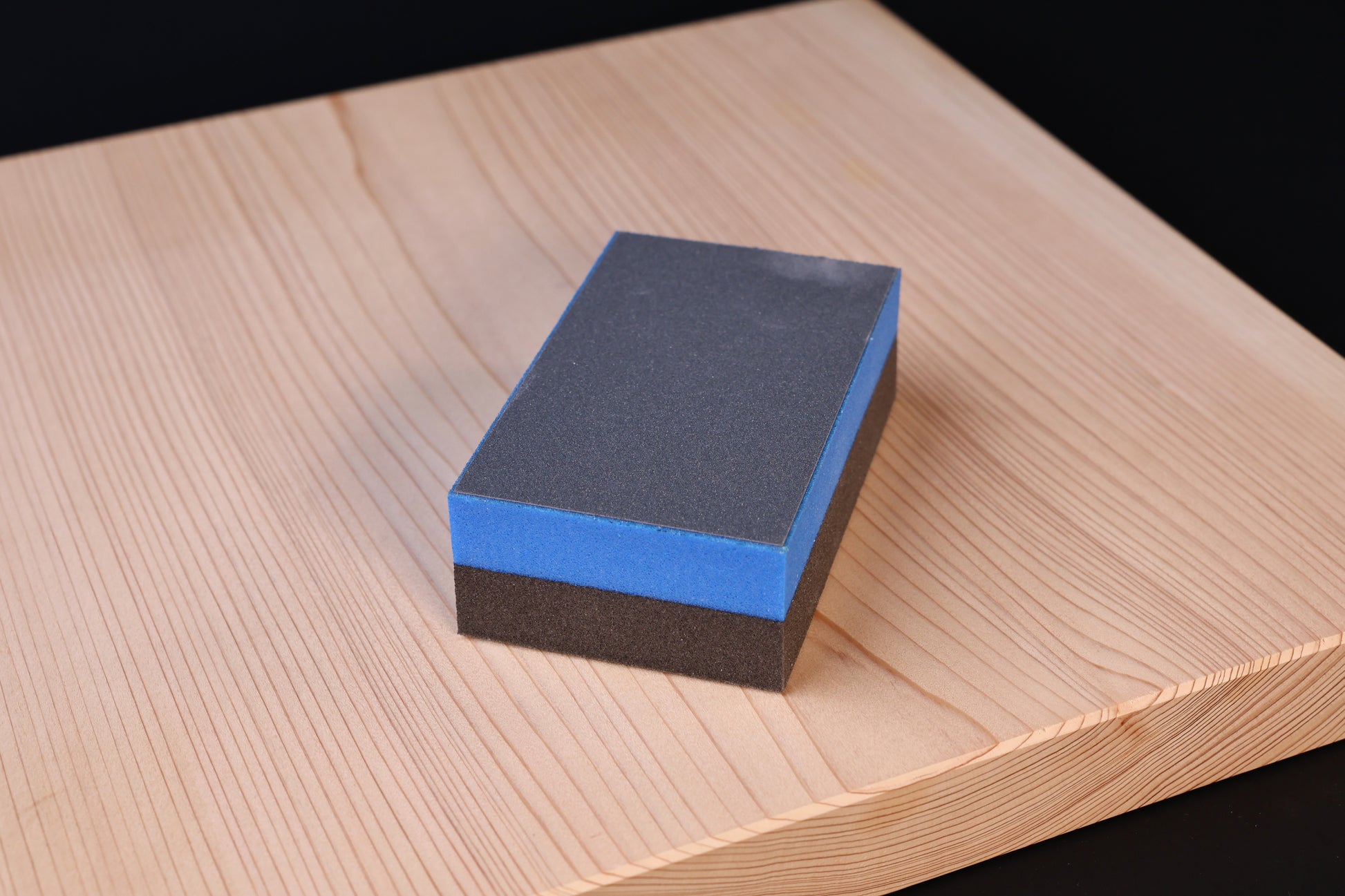 Kato Sangyo cutting board scraper — top view on hinoki board showing fine abrasive face and blue foam layer