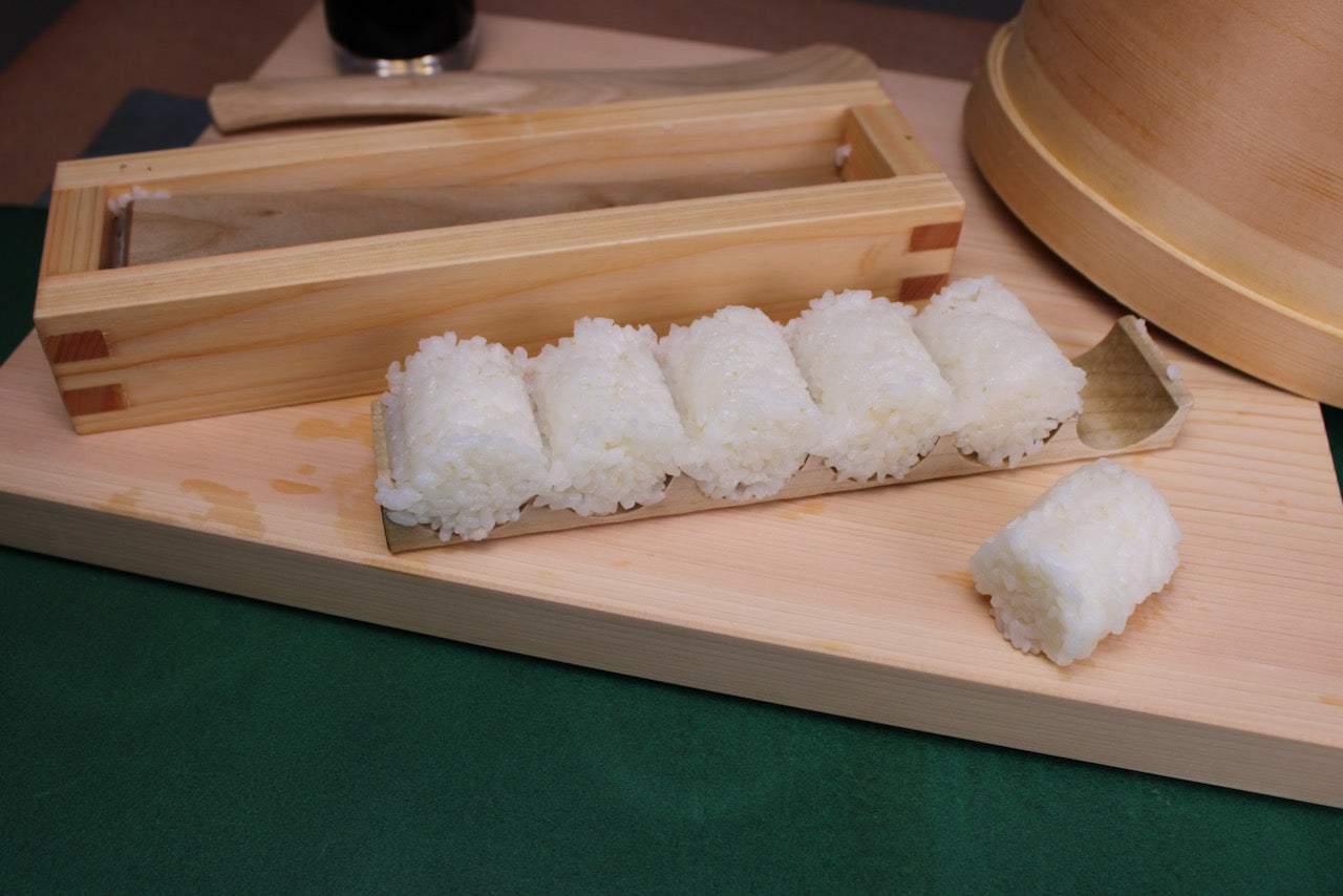 yamacoh bale shaped onigiri maker with barrel shaped prepared rice with kitchen backdrop 