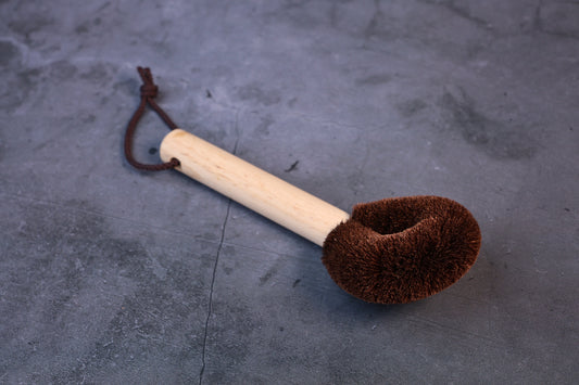 Kitayama Masatsumu palm-fiber tawashi brush shown at an angle with the wooden handle and brown cord loop
