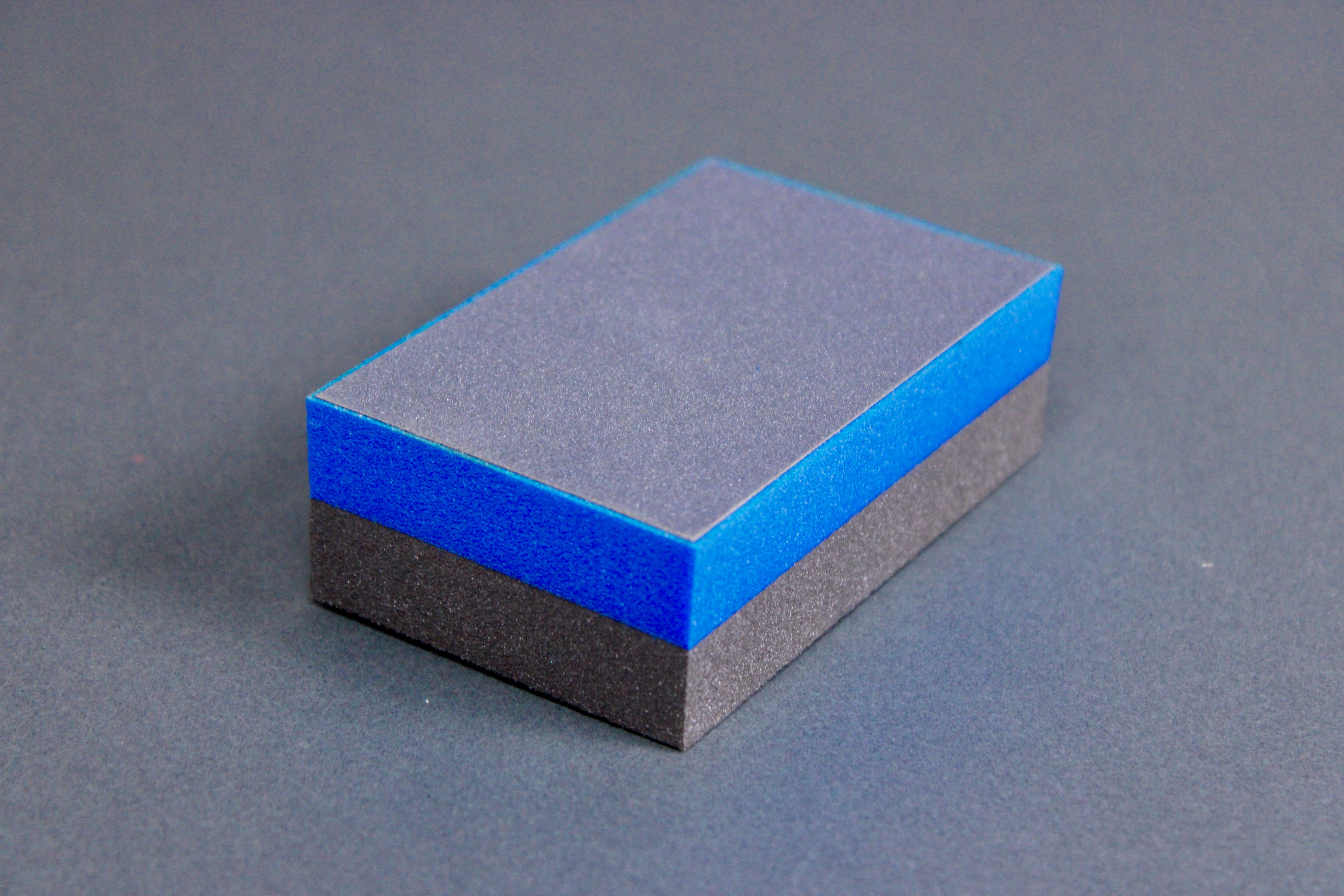 rectangular half black half blue cutting board scrapper sitting atop grey surface