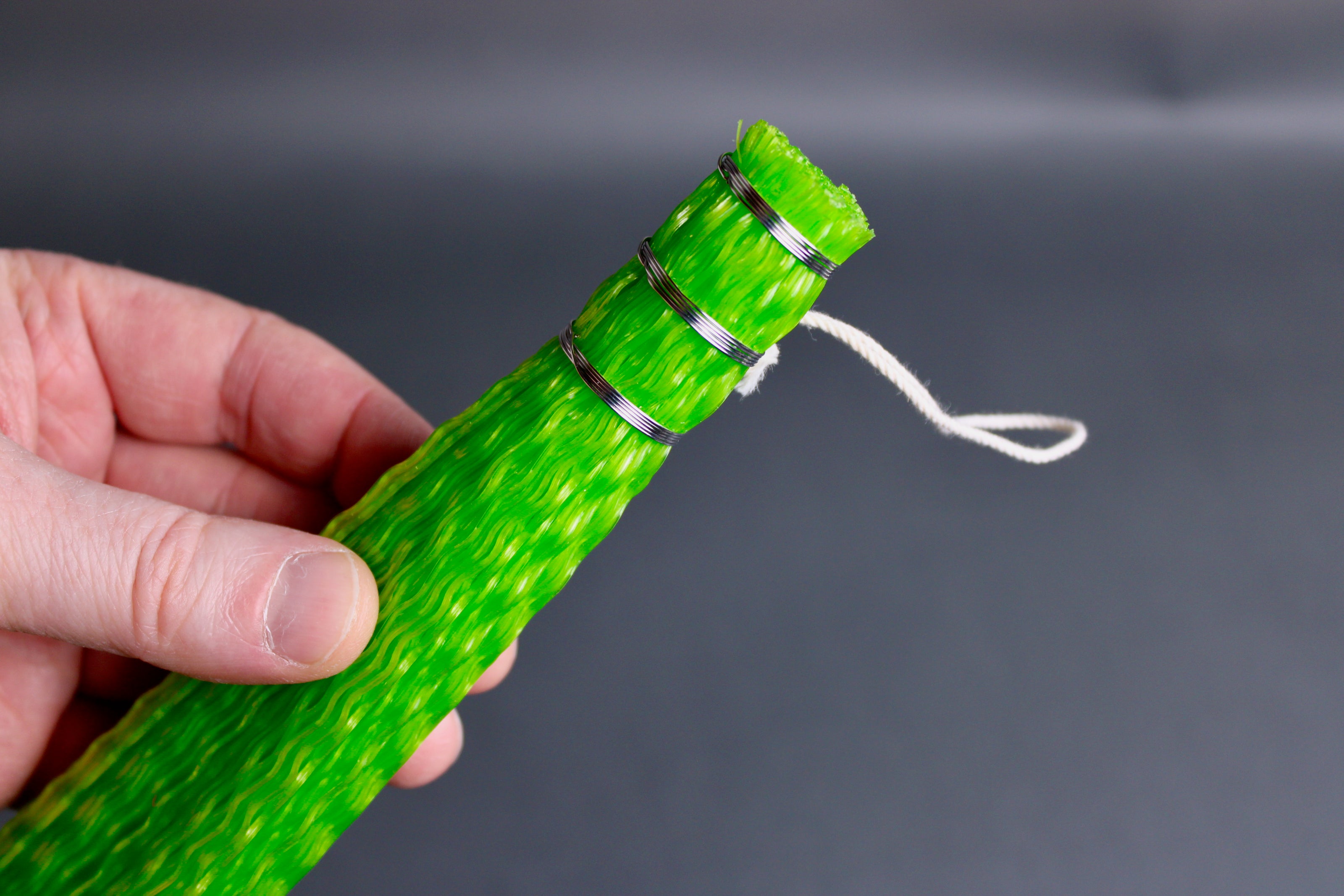 hand holding bright green plastic brush on grey surface