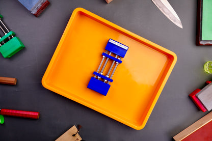 yellow orange colored short plastic knife sharpening box with rubber plastic whetstone holder blue inside surrounded by knife sharpening items grey surface