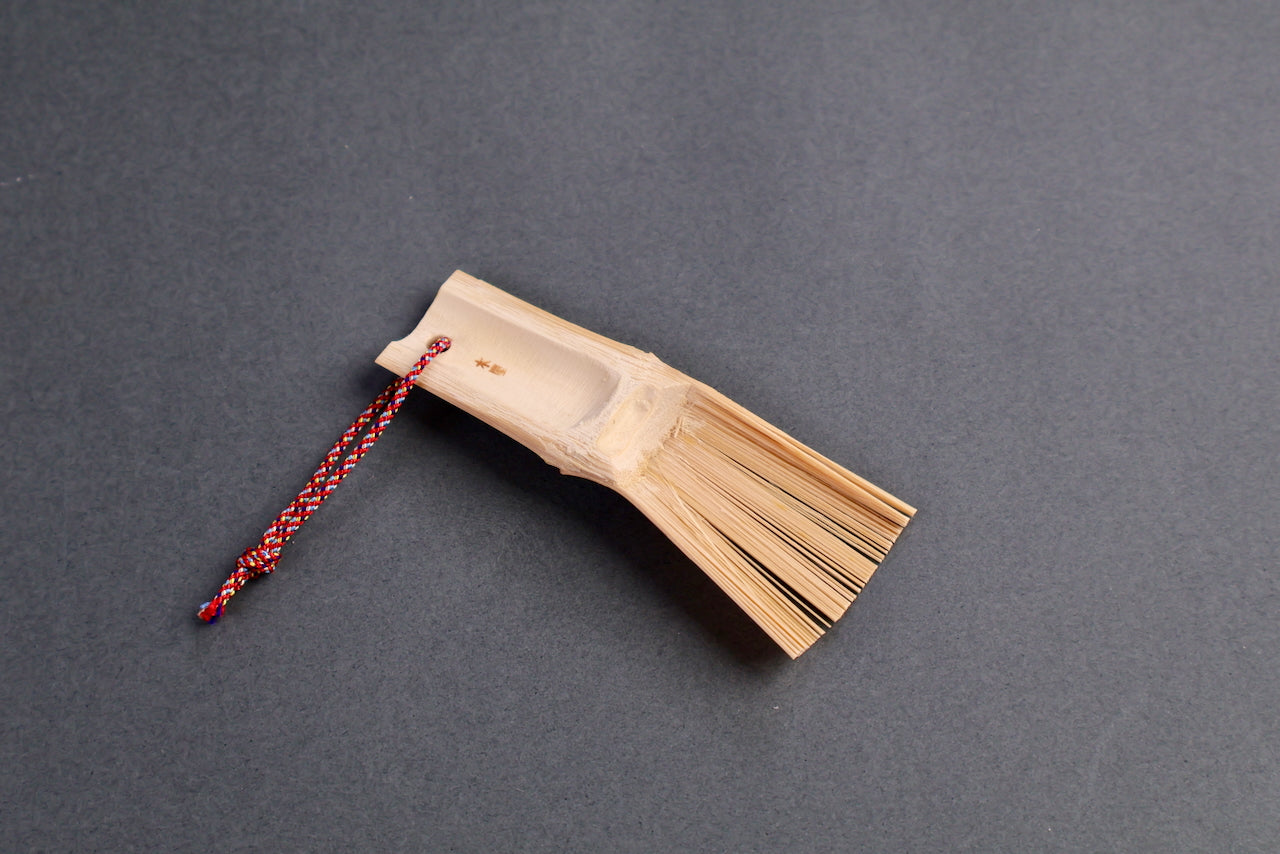 small bamboo brush for wasabi ginger sesame seed handmade in Japan angled shot with dark grey background