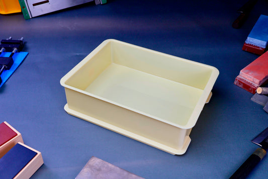 short yellow plastic sharpening box surrounded by japanese knife sharpening accessories on a bluish dark surface