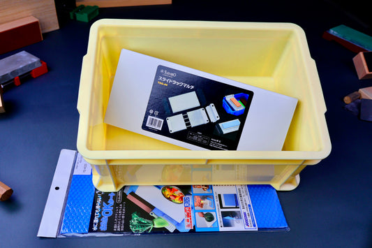 knife sharpening station with bright yellow container suehiro box hasegawa non slip mat surrounded by knife accessories backdrop 