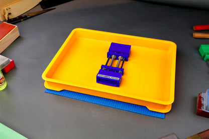 short wide yellow sharpening box atop blue hasegawa mat with whetstone holder inside in grey background