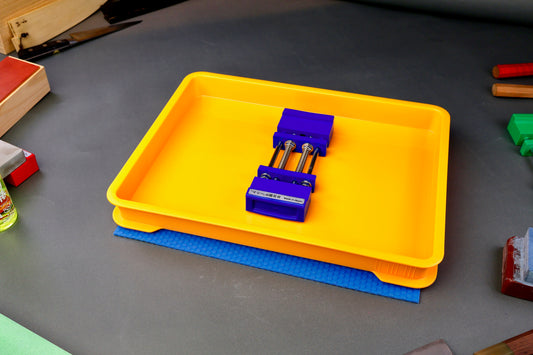 short wide yellow sharpening box atop blue hasegawa mat with whetstone holder inside in grey background