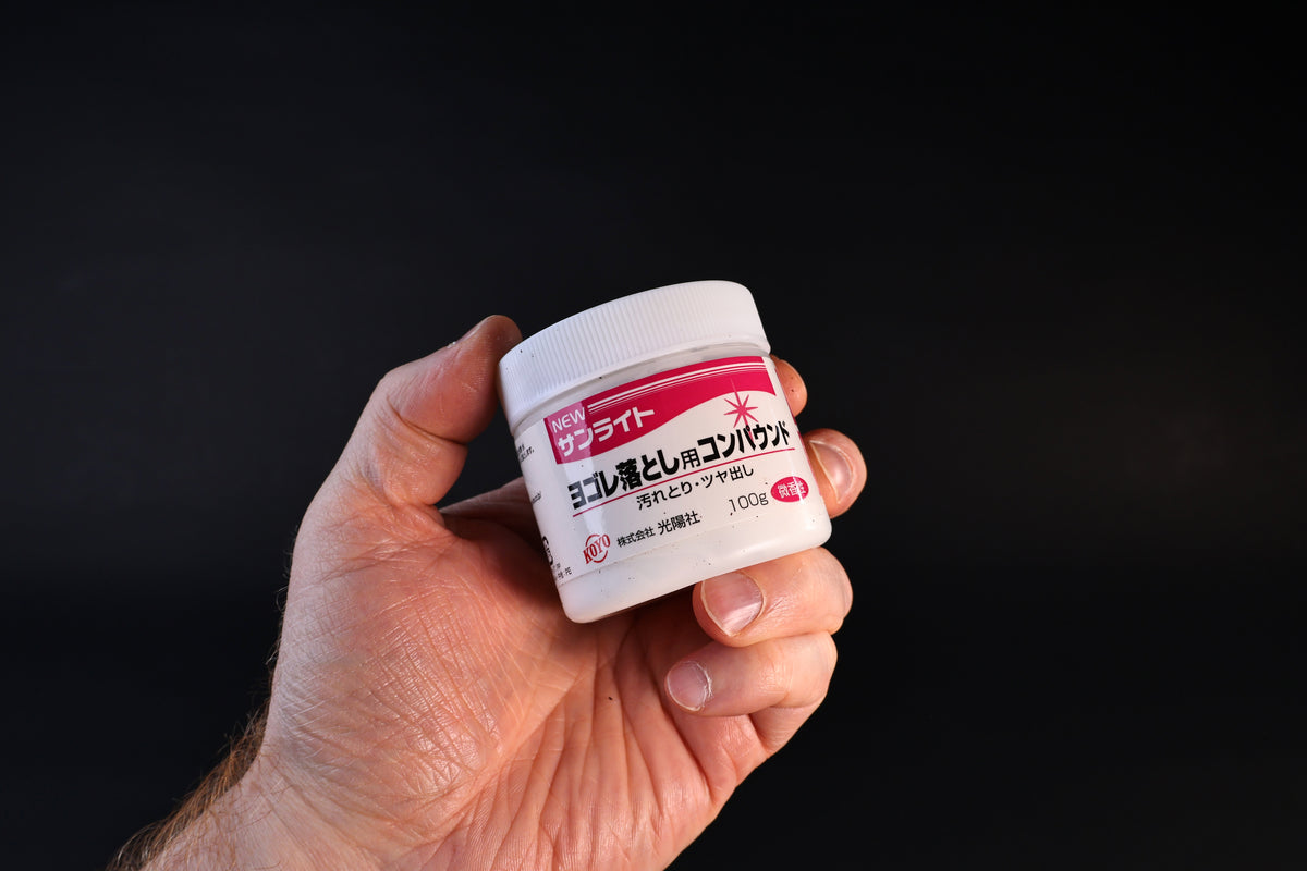 Koyo New Sunlite dirt-removing polishing compound in a 100g white jar with red label, held against a dark background