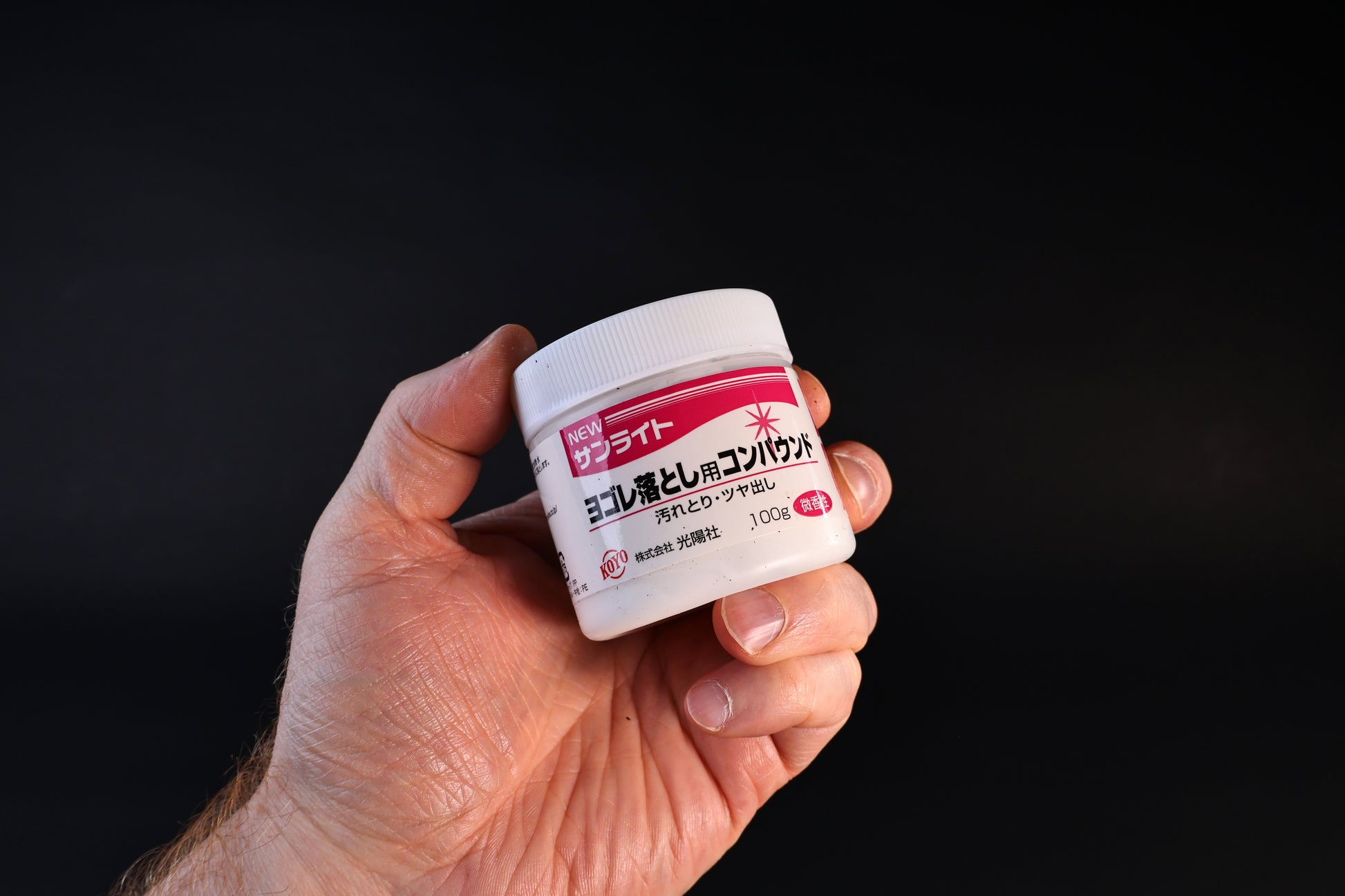 Koyo New Sunlite dirt-removing polishing compound in a 100g white jar with red label, held against a dark background