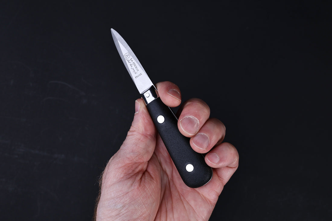 Laguiole Neron oyster knife — full side view showing blade, bolster, and handle on wood surface