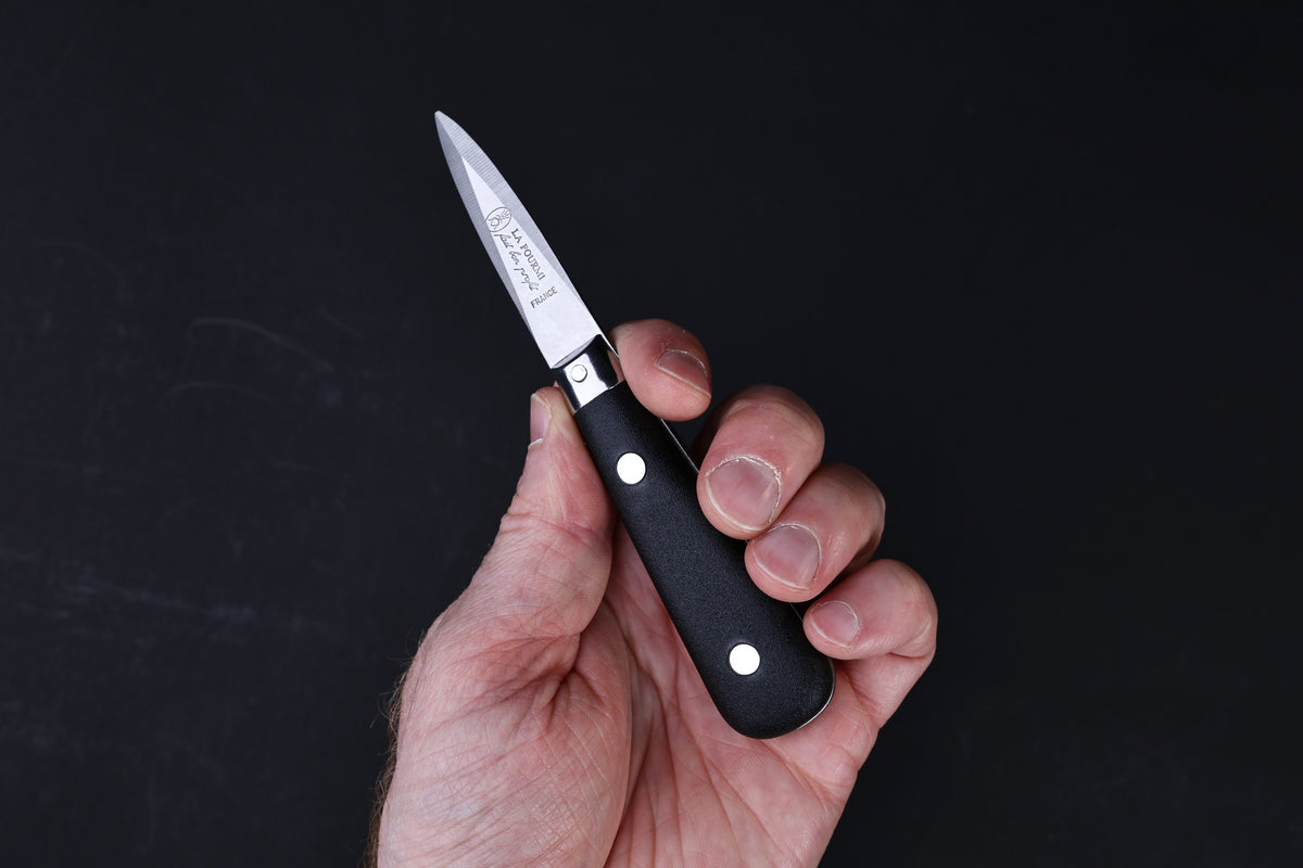 Laguiole Neron oyster knife — full side view showing blade, bolster, and handle on wood surface