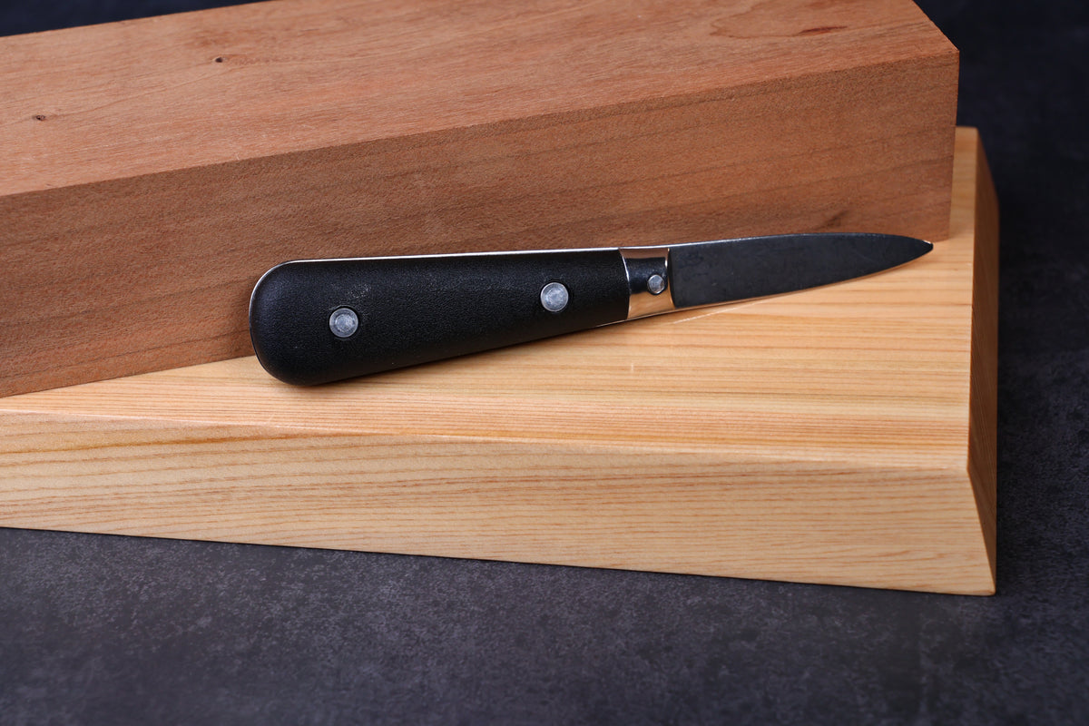 Laguiole Neron oyster knife — handle shape, rivets, and bolster detail resting on wood surface