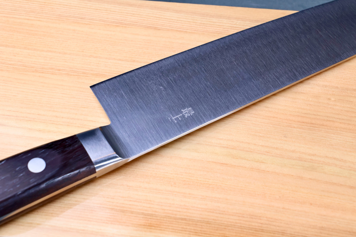 Masamoto CT carbon steel gyuto 240mm blade flat on hinoki board showing grind and kanji marking