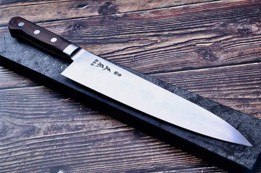 Masamoto CT carbon steel gyuto 240mm full profile on dark rustic wood background