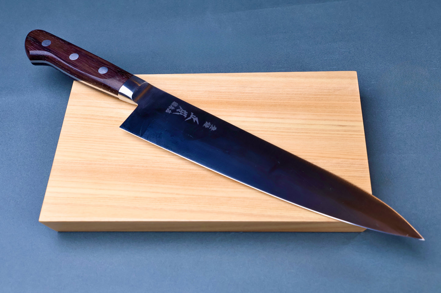 Masamoto CT carbon steel gyuto 240mm resting on hinoki cypress cutting board
