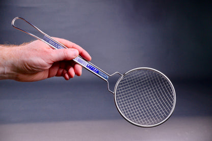 hand holding long handled sturdy coarse metal skimmer with hiragana writing on grey background