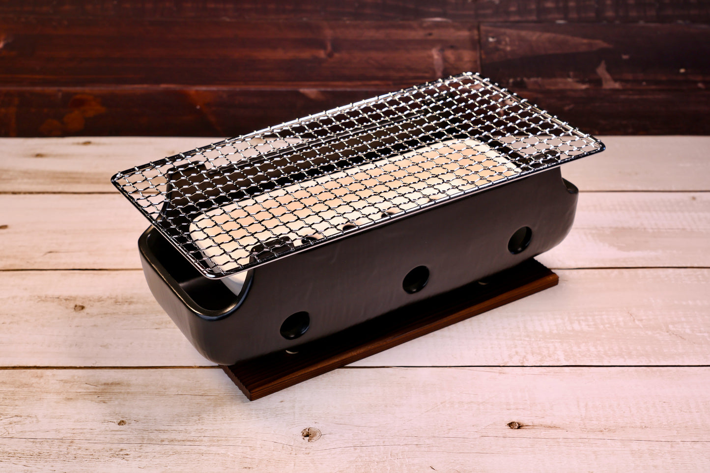 Misuzu Pottery Banko Yaki Konro Grill, three-quarter angled view showing black ceramic body, wire grate, and wood base