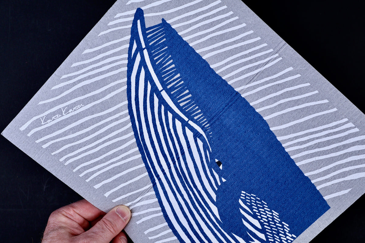 Morikatsu Katakata whale towel held close showing blue whale print detail and texture against black background