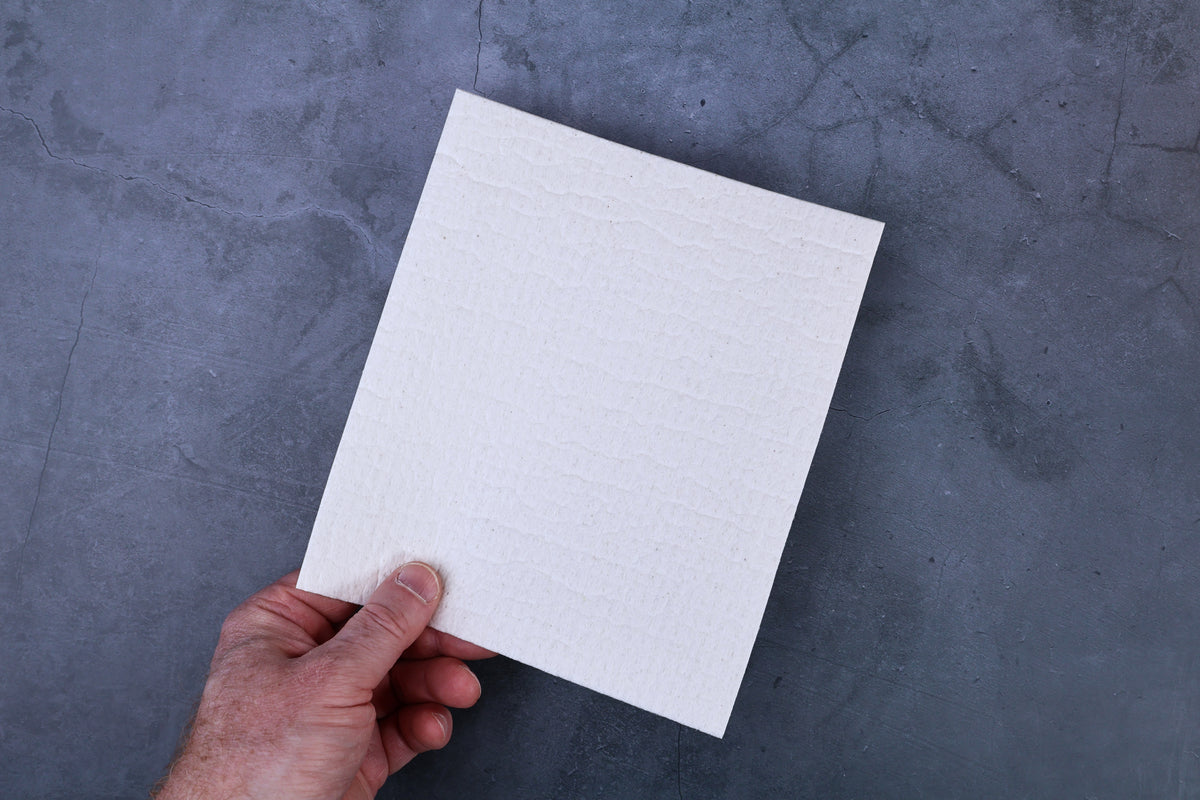 Morikatsu kitchen towel held in hand showing size and textured surface against grey background