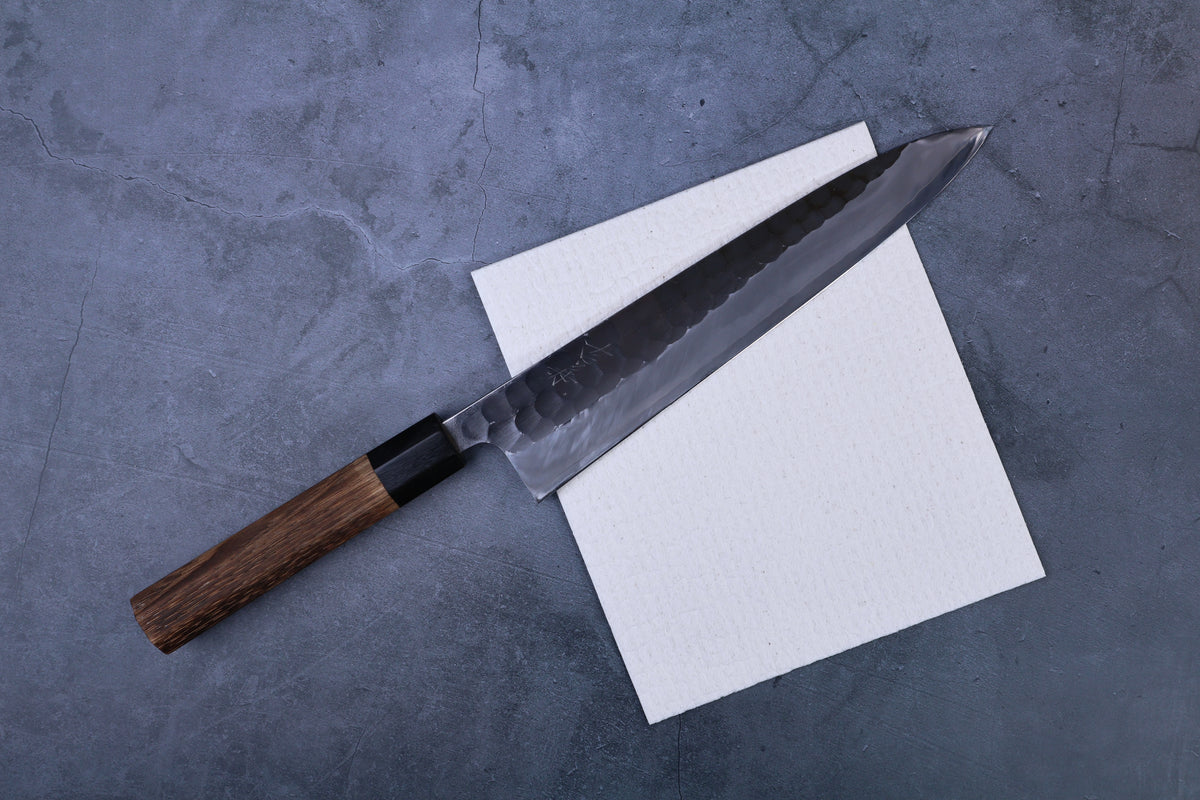 Morikatsu kitchen towel laid flat with Japanese gyuto knife resting on top, grey concrete background