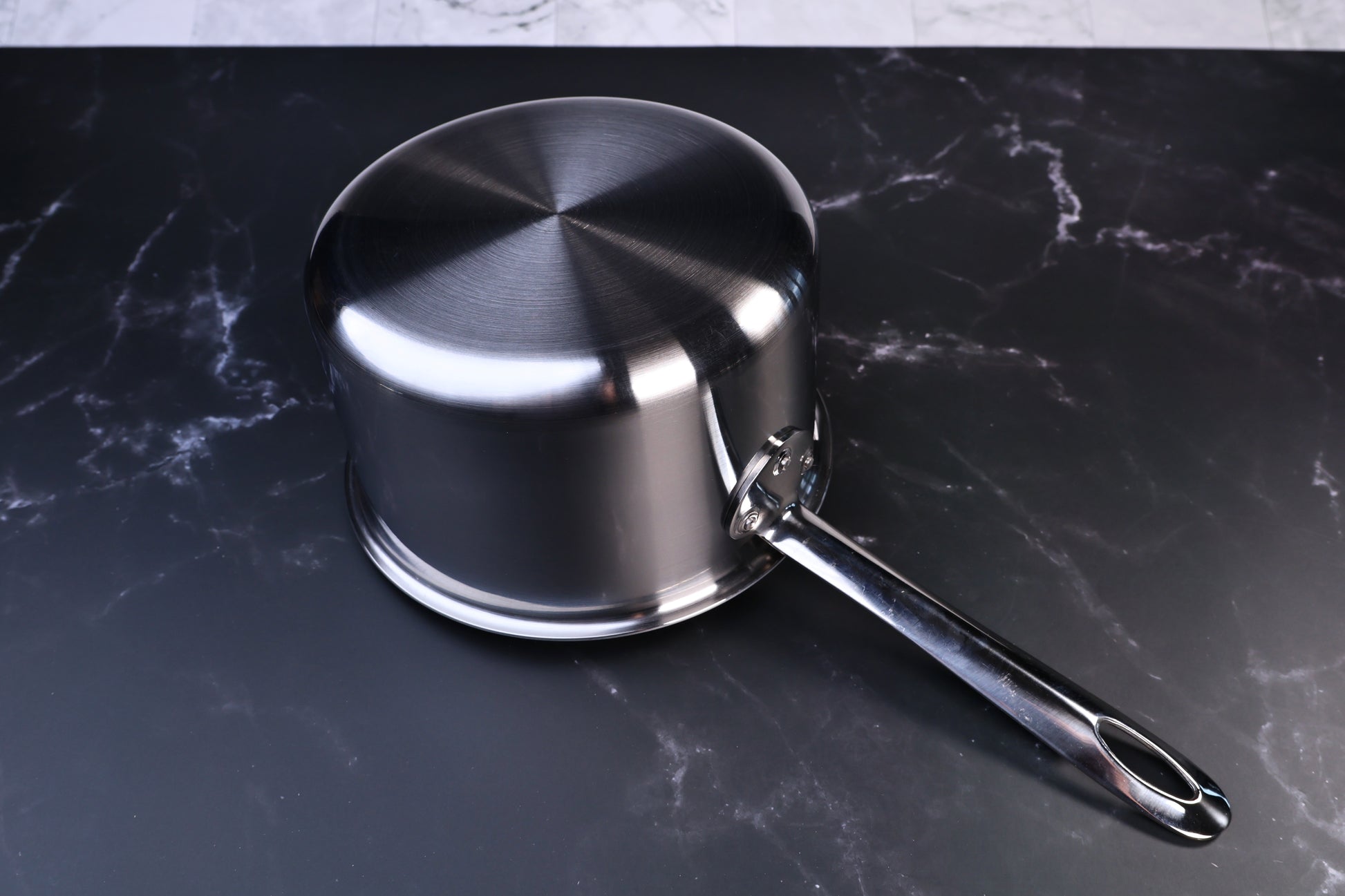 Mt. Fuji Steel Clad saucepan 18cm exterior showing brushed stainless clad bottom and long handle on marble