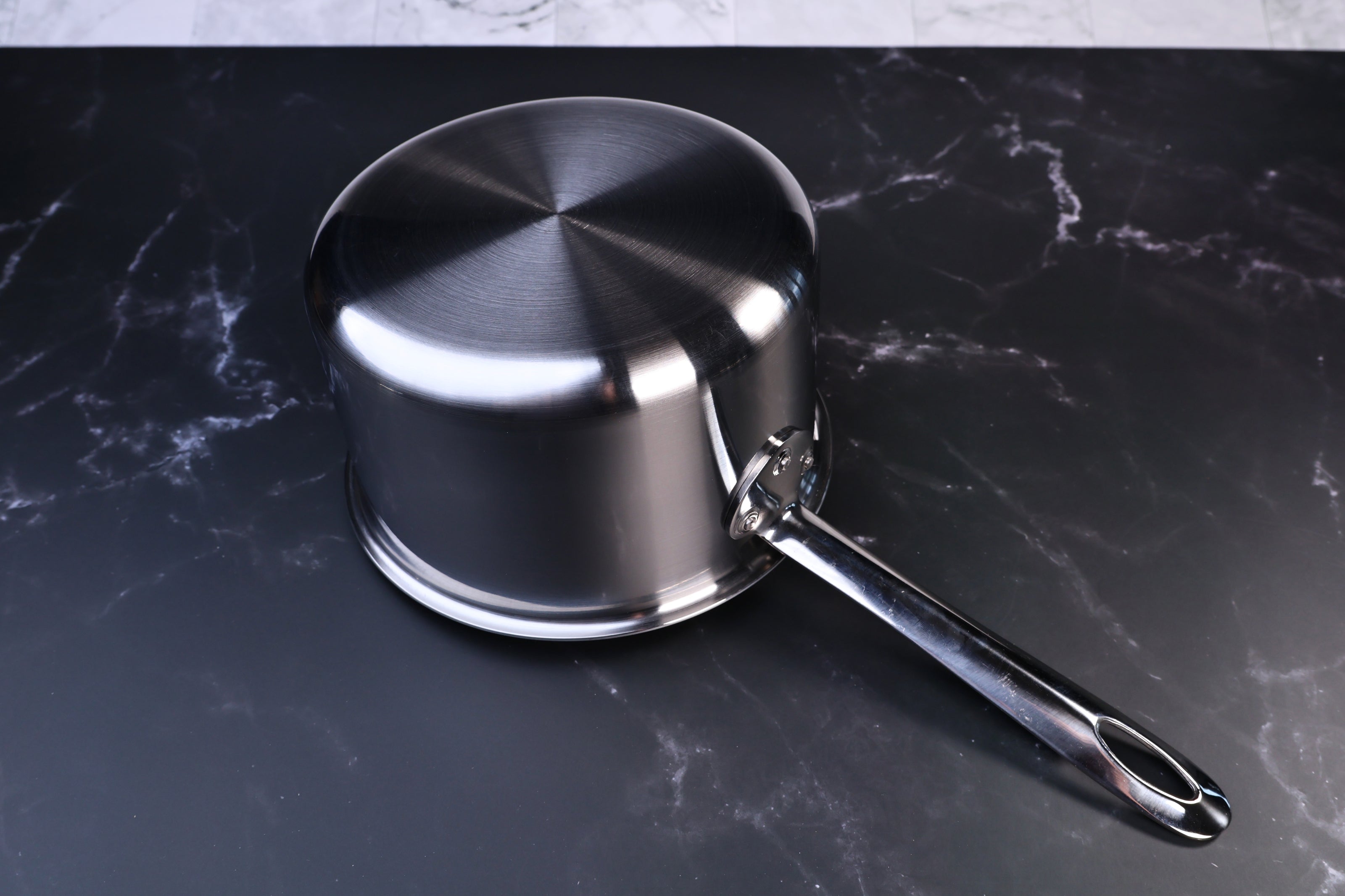 Mt. Fuji Steel Clad saucepan 18cm exterior showing brushed stainless clad bottom and long handle on marble