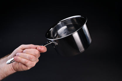 Mt. Fuji Steel Clad saucepan 18cm held in hand showing interior, straight walls, and size on black background