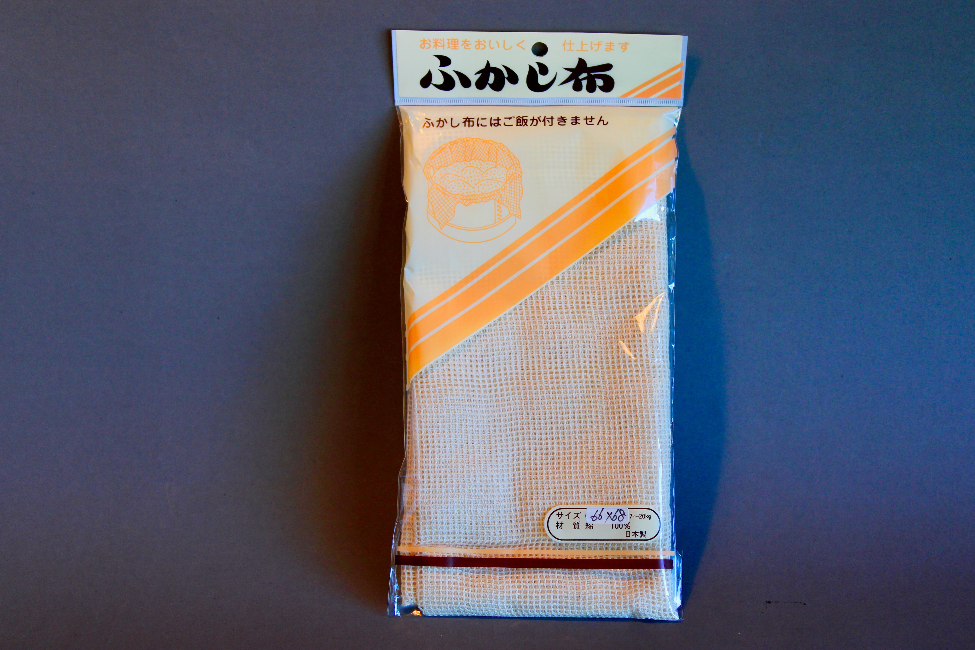long rectangular product plastic wrapped steam cloth with printed name in hiragana animated steamer with tan and yellow stripes on grey backdrop