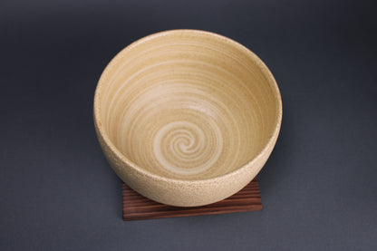 top down image of iga ware vessel with spiral designed lines the yellowish white tone contrasts with dark grey backdrop