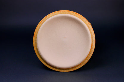 round yellowish lid with white center standing in grey background